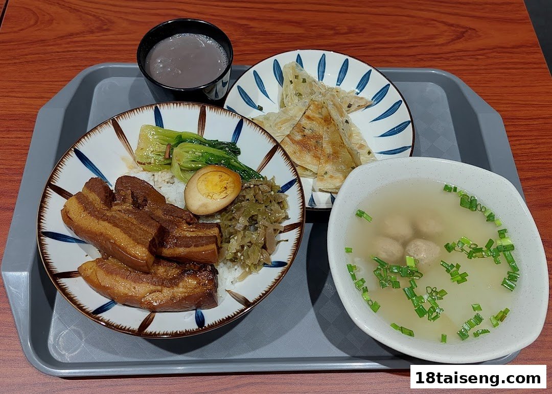 A delicious Taiwanese meal featuring braised pork rice, soup, scallion pancake, and a drink on a tray.