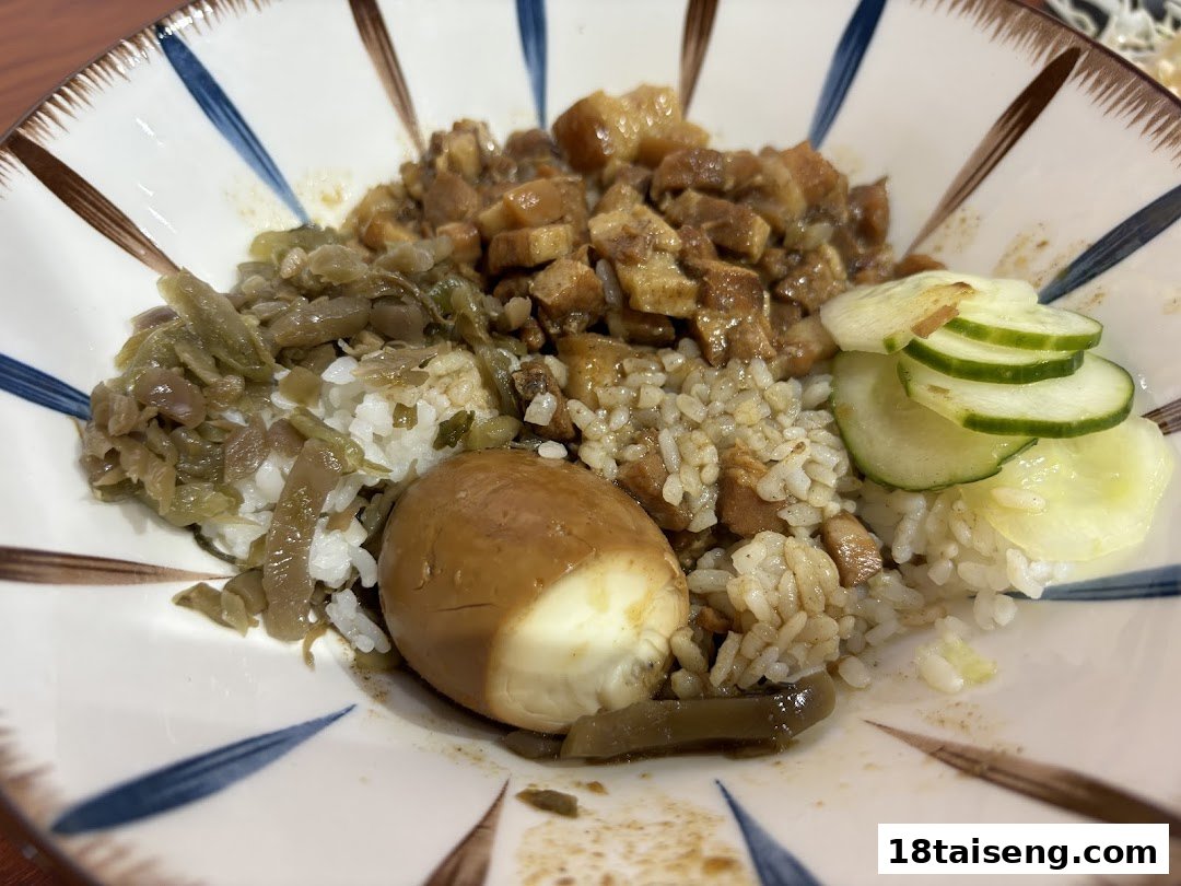 A close-up of a bowl of Taiwanese braised pork rice (Lu Rou Fan) with a tea egg and pickled vegetables.