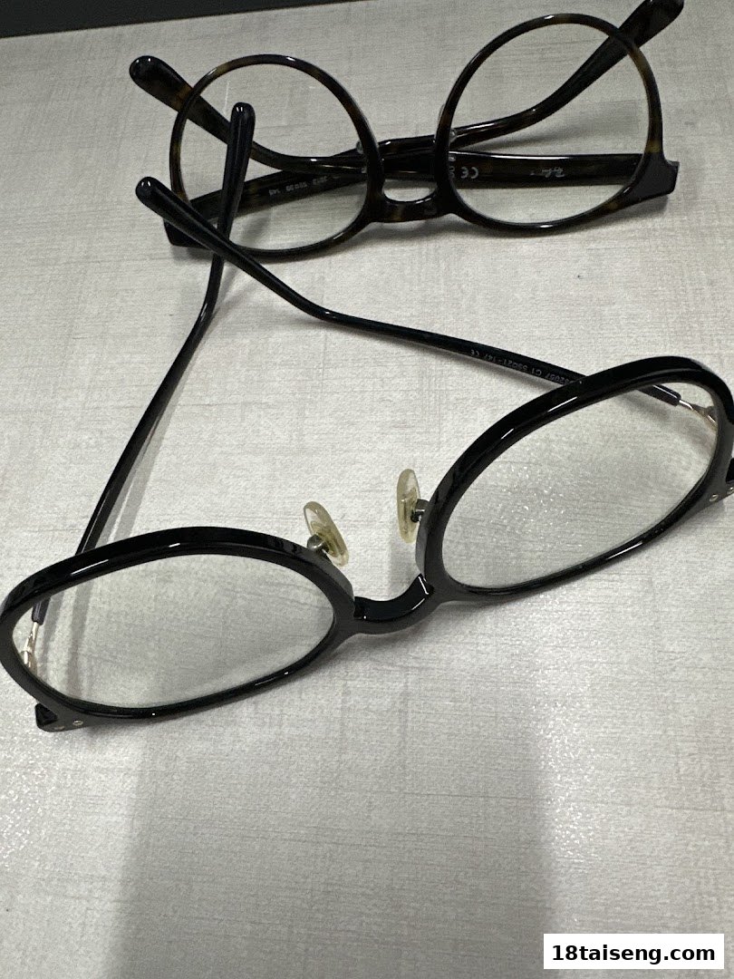 Two pairs of stylish eyeglasses, one black and one tortoiseshell, displayed on a light surface.