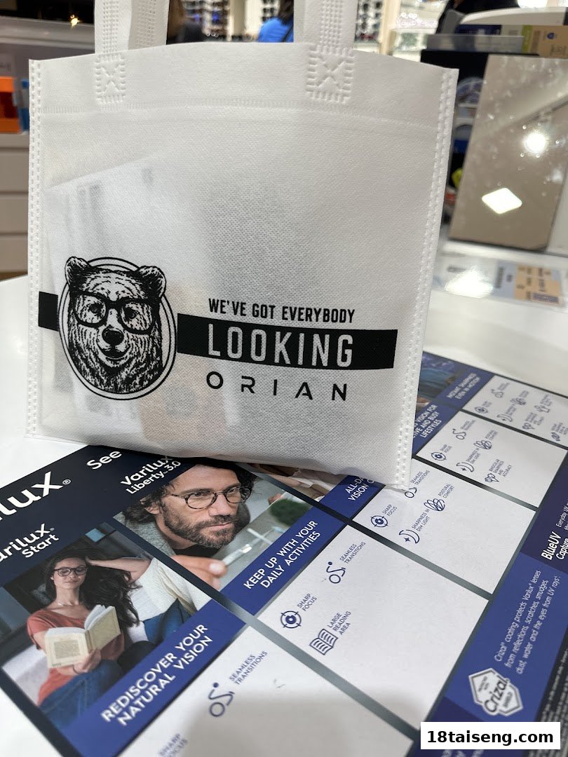A white shopping bag with 'ORIAN LOOKING' logo and Varilux promotional material on a counter.