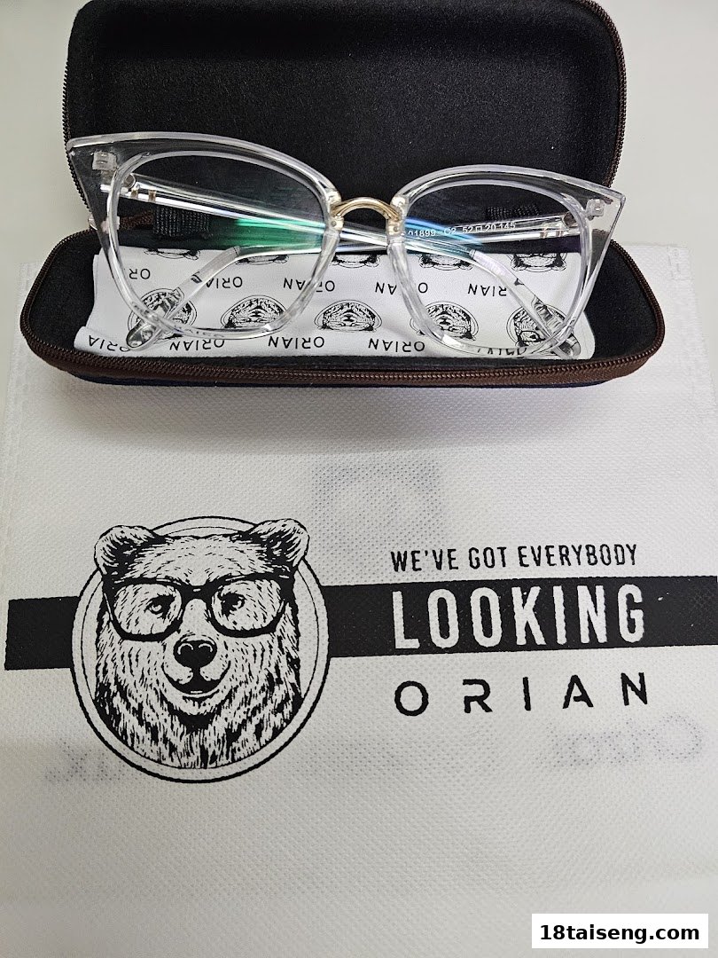 Clear eyeglasses in a case on a branded Orian bag with a bear logo.