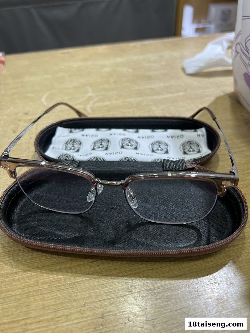 A pair of stylish eyeglasses in an open case on a wooden table.