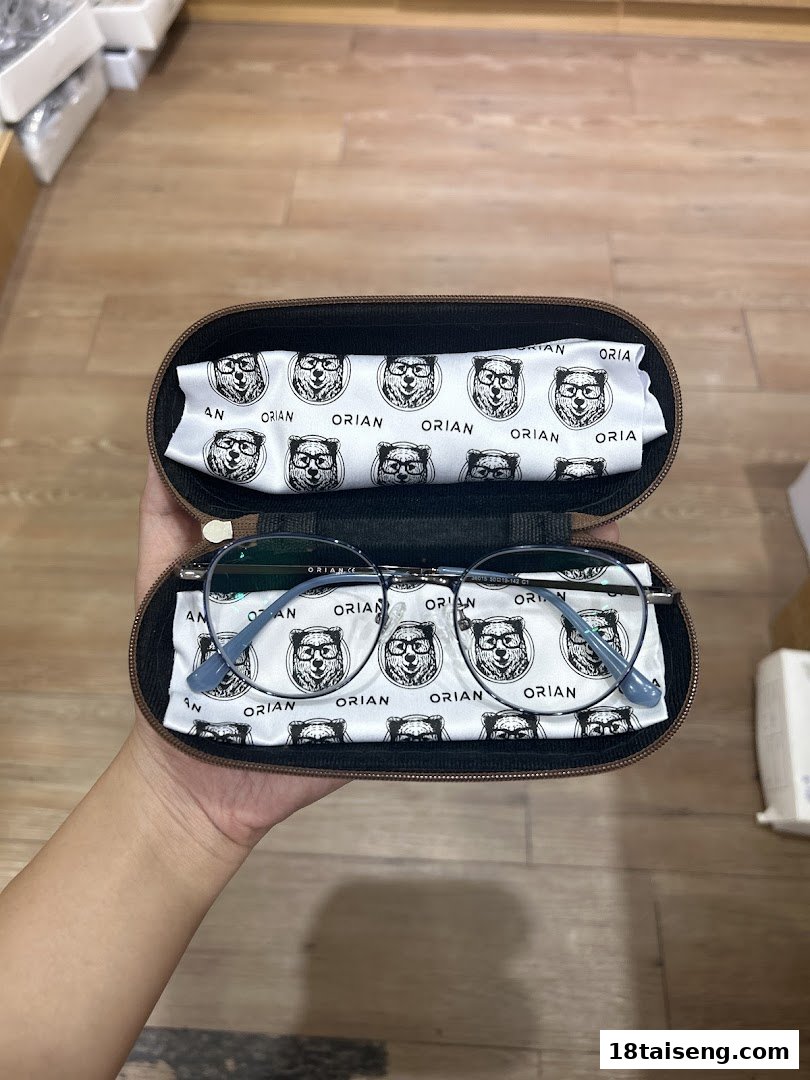 A hand holds a pair of Orian eyeglasses in their branded case with a bear logo.