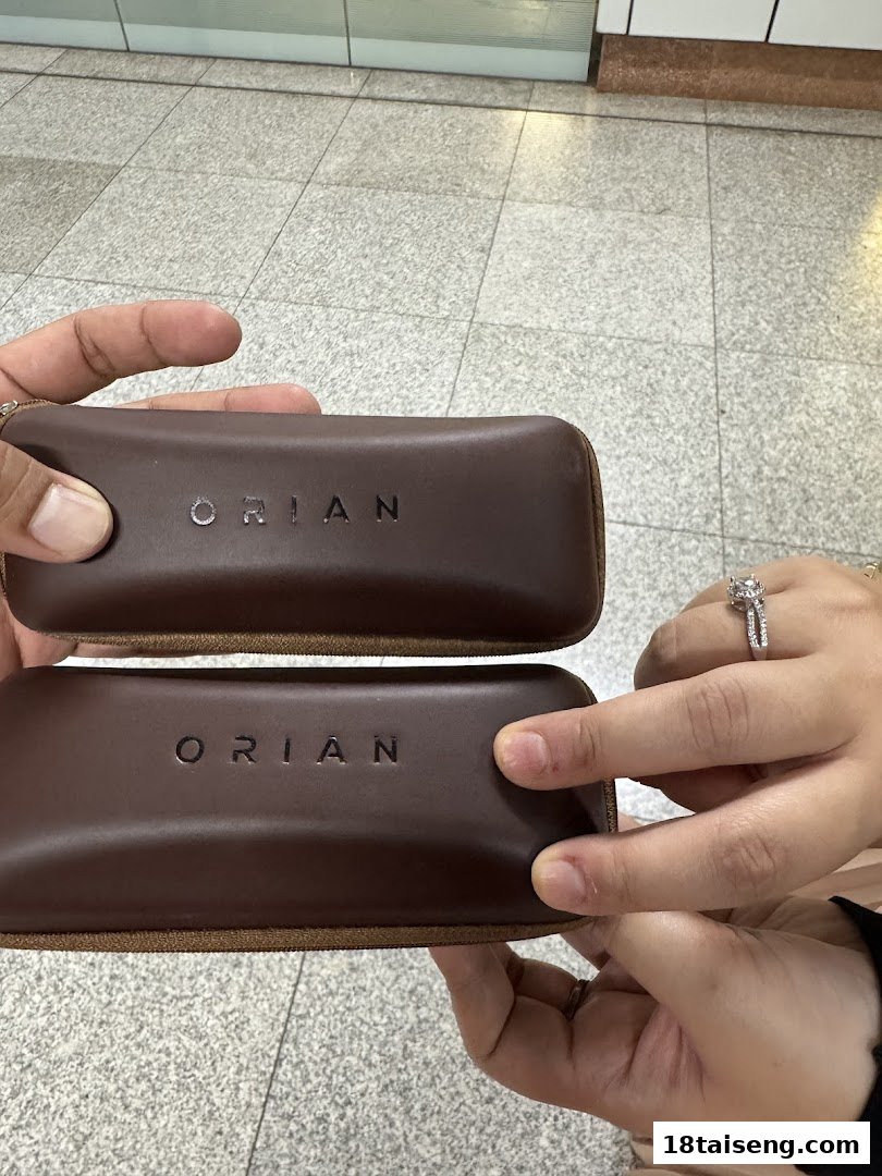Two brown cases with 'ORIAN' branding held by hands, showcasing the product packaging.