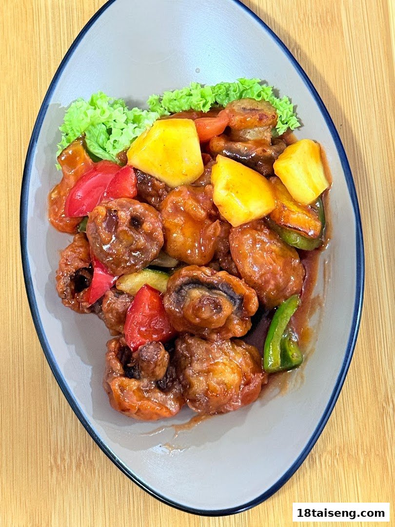 A vibrant plate of sweet and sour vegetarian dish with mushrooms, pineapple, and bell peppers.