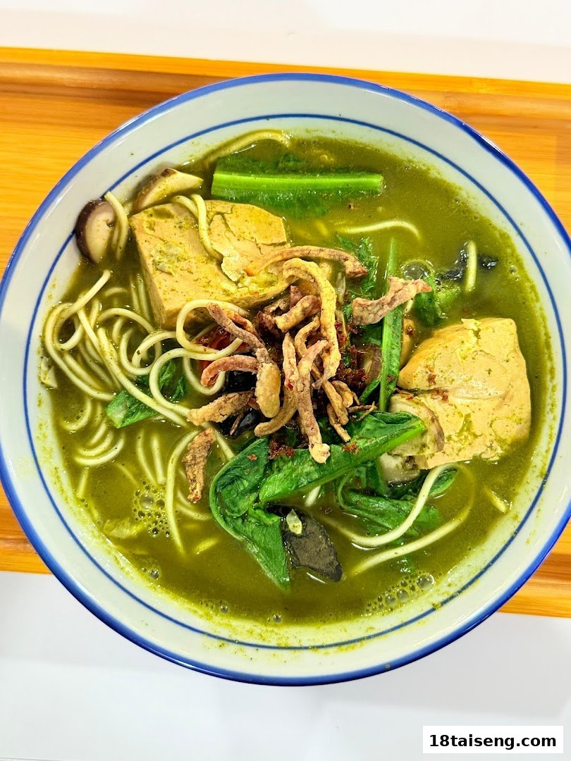 A vibrant bowl of green soup noodles with tofu, mushrooms, and greens from Peace Vegetarian.
