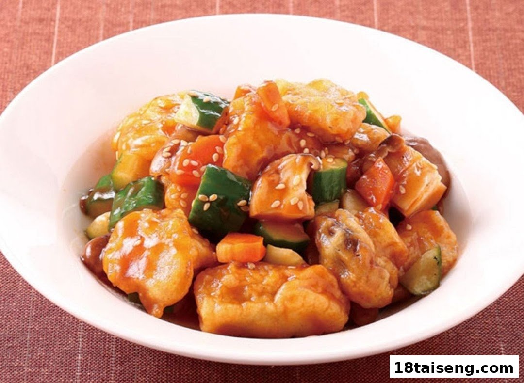A vibrant bowl of sweet and sour vegetarian dish with mock meat, vegetables, and sesame seeds.