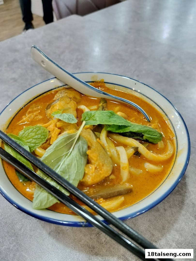 A vibrant bowl of vegetarian curry noodles with fresh herbs and a spoon, ready to be enjoyed.