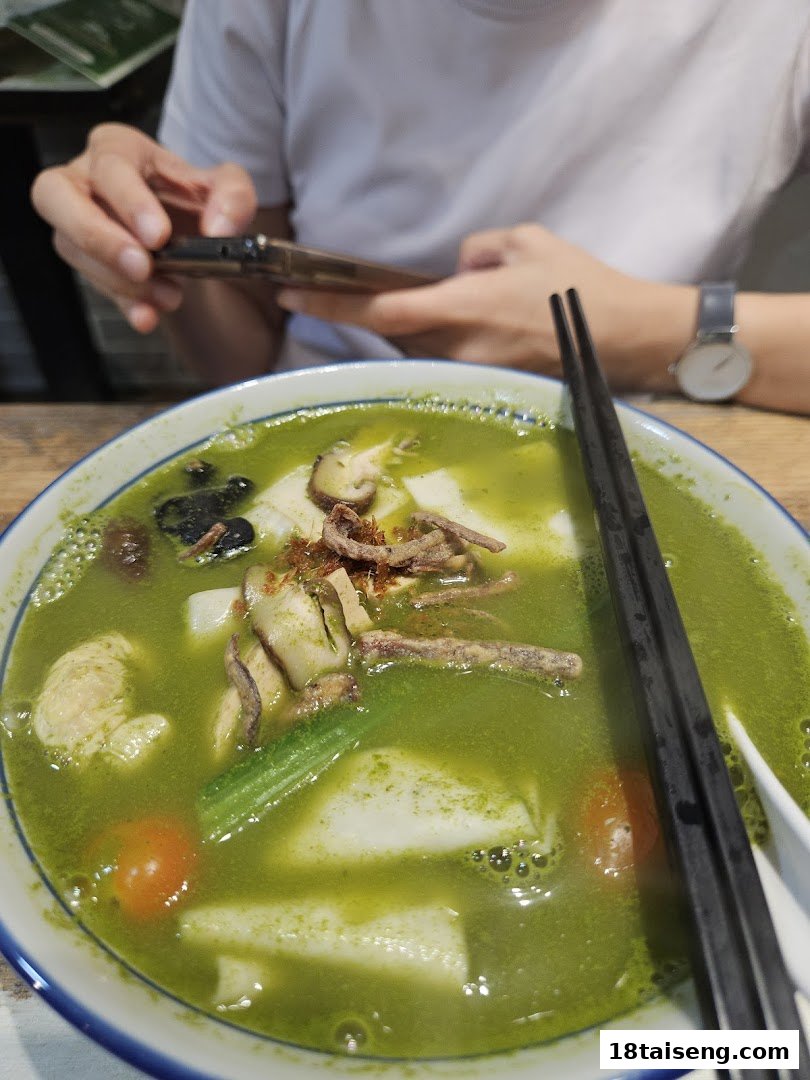 A vibrant green vegetarian noodle soup with mushrooms, vegetables, and tofu, ready to be enjoyed.