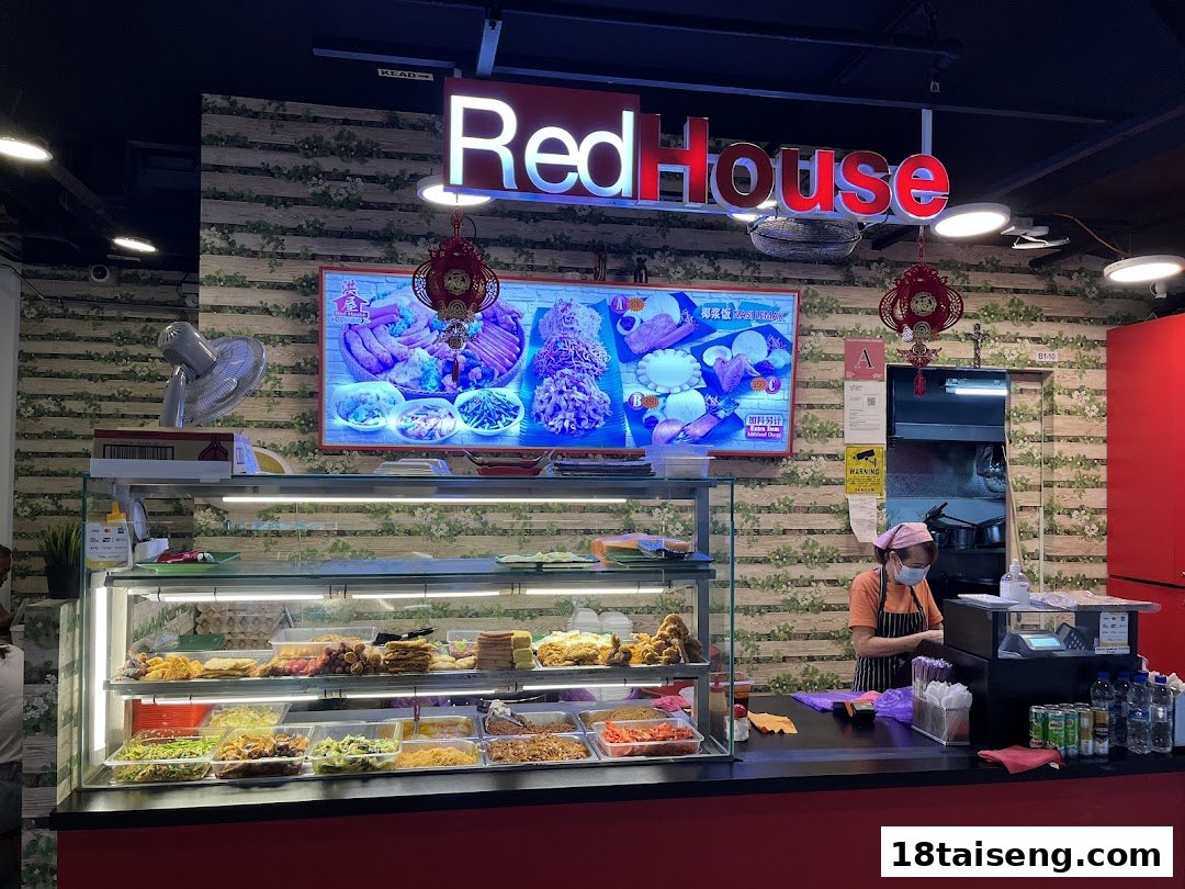 A vibrant interior shot of Red House, showcasing a food display counter and a staff member.