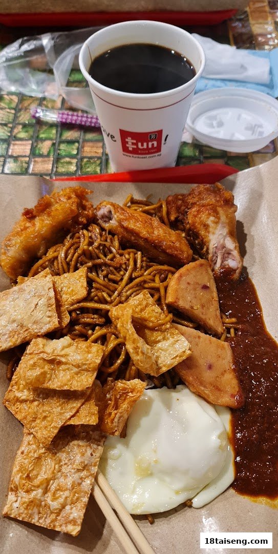 A delicious plate of dark noodles with fried chicken, egg, and bean curd, served with a cup of coffee.