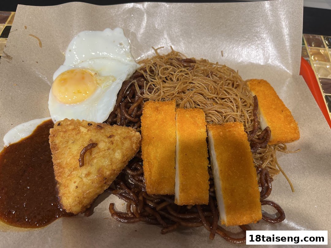 A delicious plate of dark sauce noodles with a fried egg, hash brown, and crispy fish cakes.