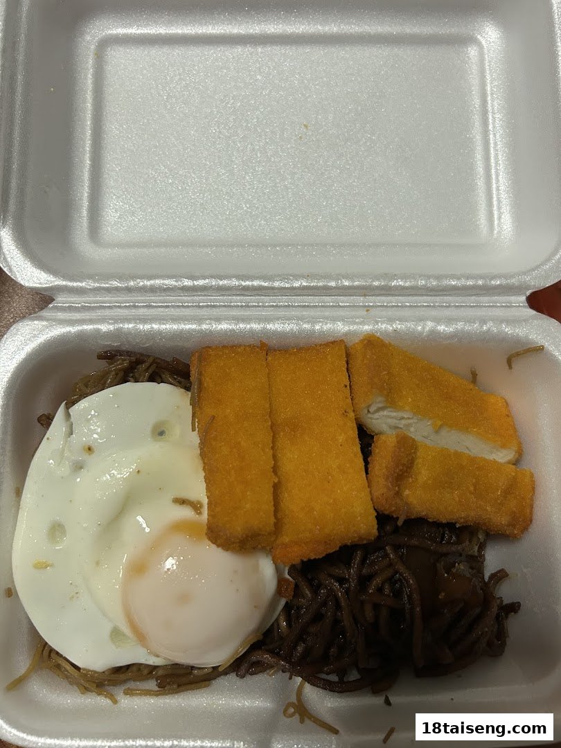 A takeout container filled with noodles, a fried egg, and breaded chicken pieces.