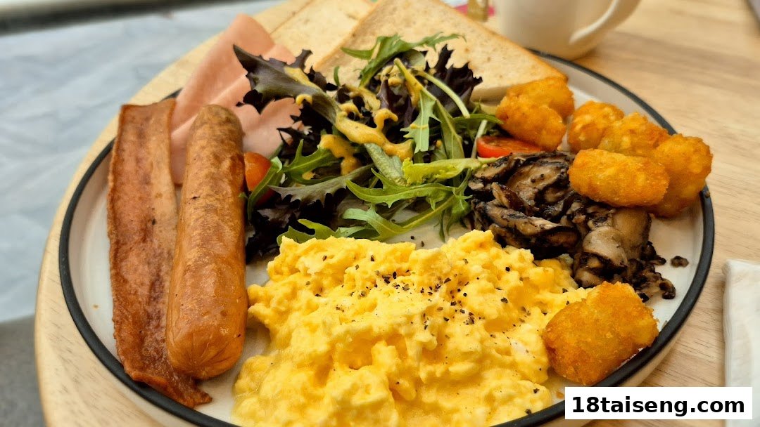 A hearty breakfast platter featuring scrambled eggs, bacon, sausage, salad, mushrooms, and tater tots.