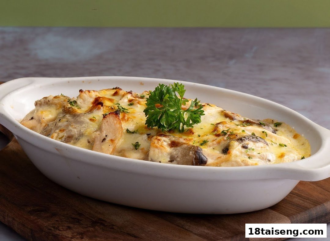 A baked dish featuring chicken, mushrooms, and melted cheese, garnished with fresh parsley, served in a white oval dish.
