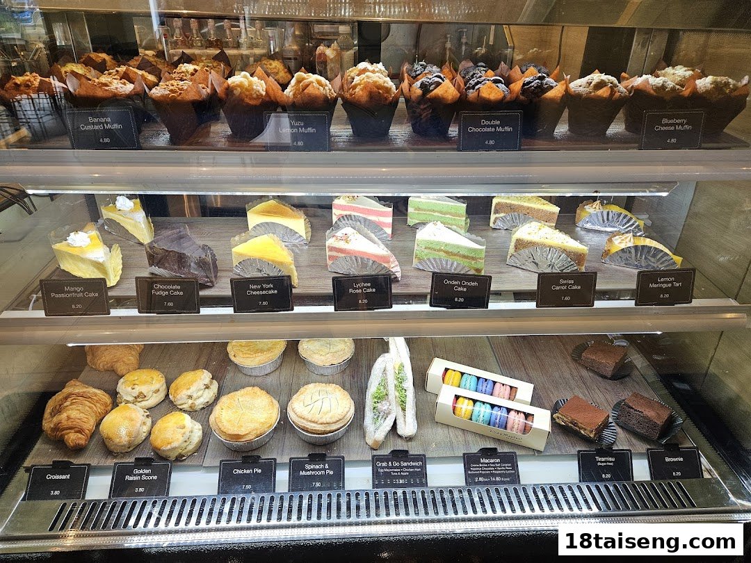 A vibrant display case showcasing a variety of freshly baked muffins, cakes, pastries, and savory pies.