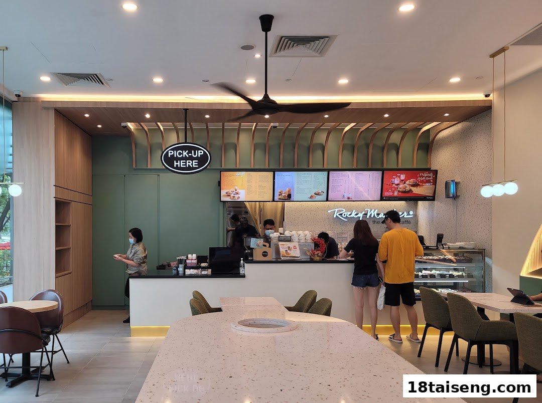 Customers at the counter of Rocky Master cafe, with digital menus and a modern interior design.