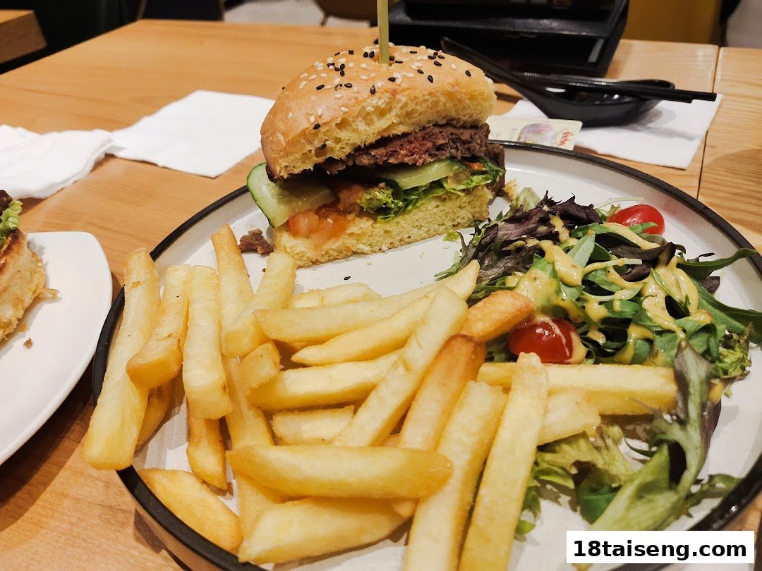 A delicious burger, golden fries, and fresh salad served on a plate.