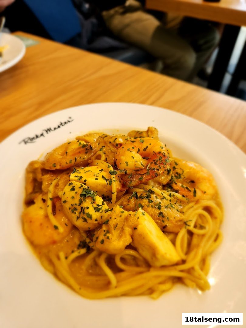 A close-up of a delicious seafood pasta dish with shrimp and squid in a creamy sauce, garnished with herbs.