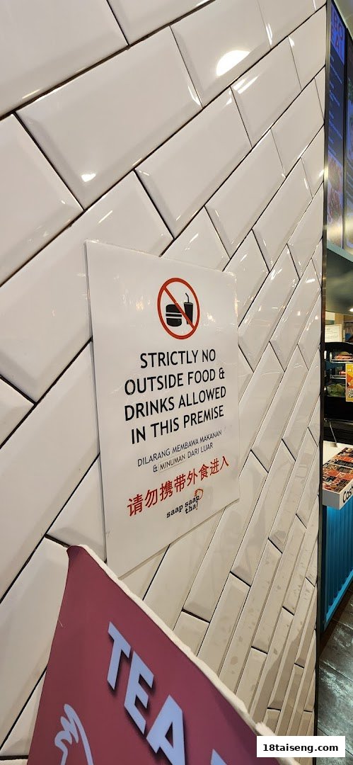 A sign on a white tiled wall stating 'No Outside Food & Drinks Allowed' inside Saap Saap Thai.