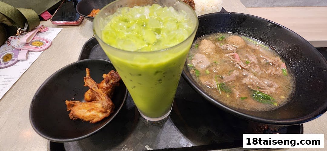 A delicious Thai meal featuring beef noodle soup, fried chicken wings, and a refreshing green drink.