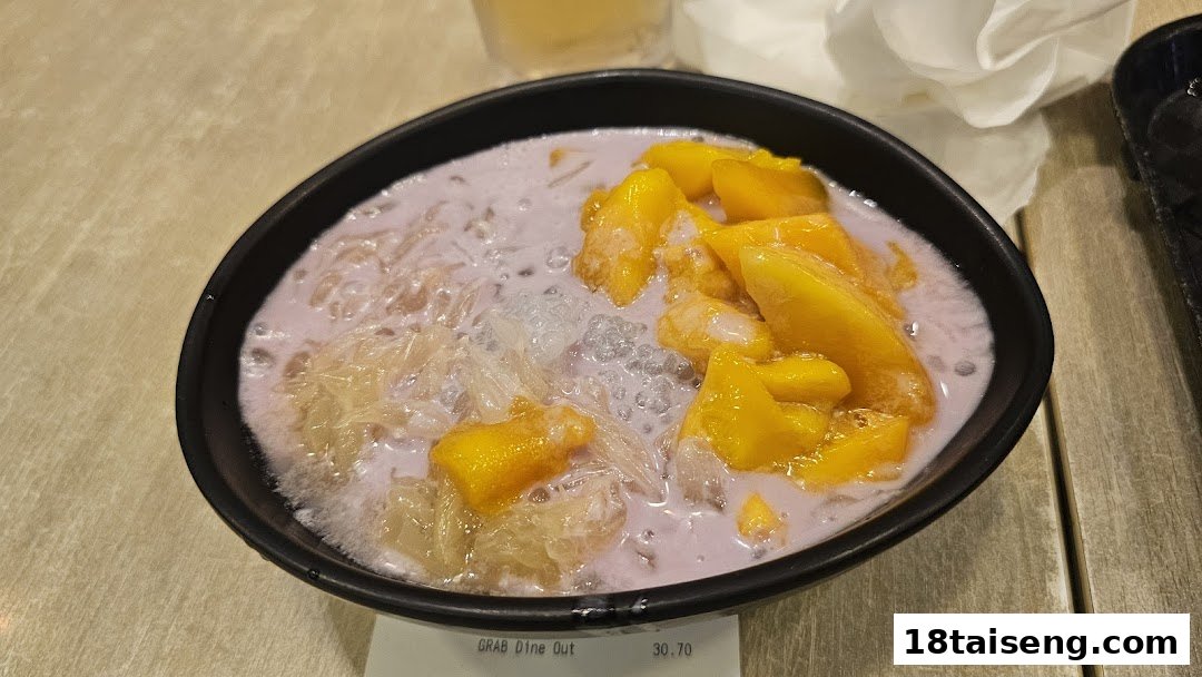 A vibrant bowl of Thai dessert with fresh mango, sago, and coconut milk.