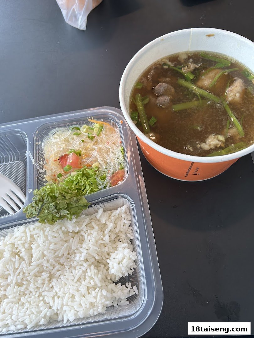 A delicious Thai meal featuring rice, vermicelli salad, and a hearty soup in takeaway containers.