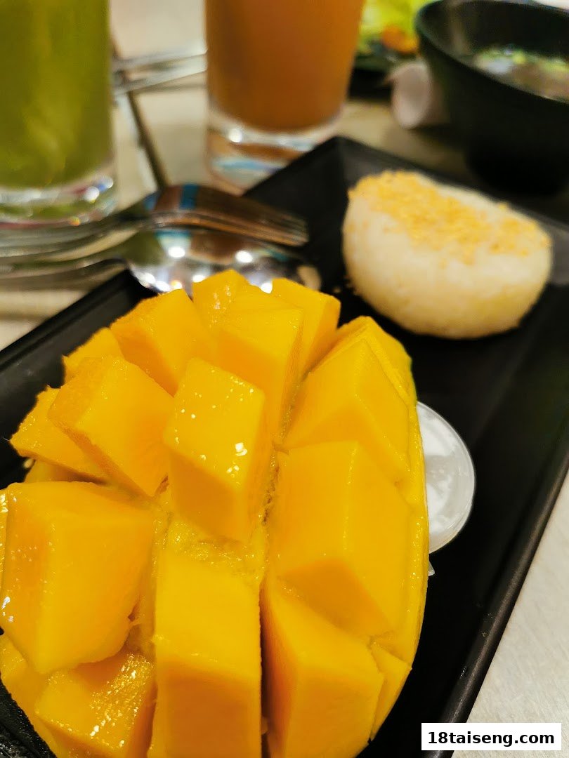 A vibrant plate of sliced mango with sticky rice, accompanied by drinks, at Saap Saap Thai.
