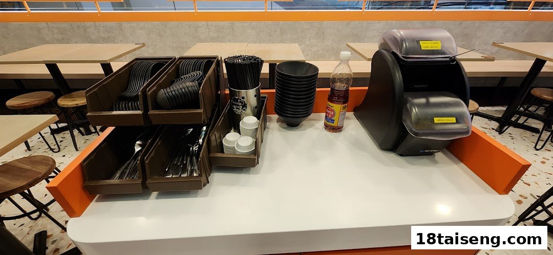 A self-service counter with cutlery, bowls, and condiments at Saap Saap Thai.