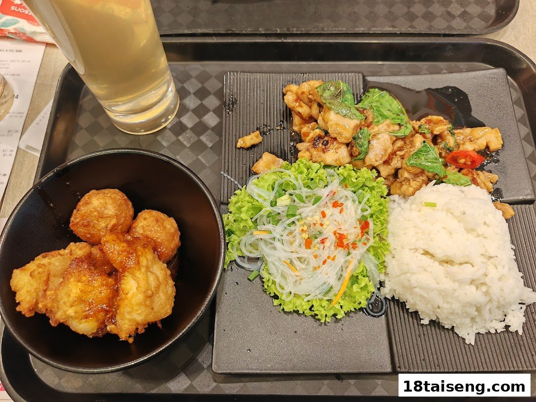 A delicious Thai meal featuring basil chicken, rice, vermicelli salad, and fried fish cakes.