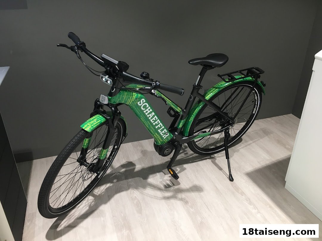 A vibrant green Schaeffler e-bike with integrated branding is displayed indoors.