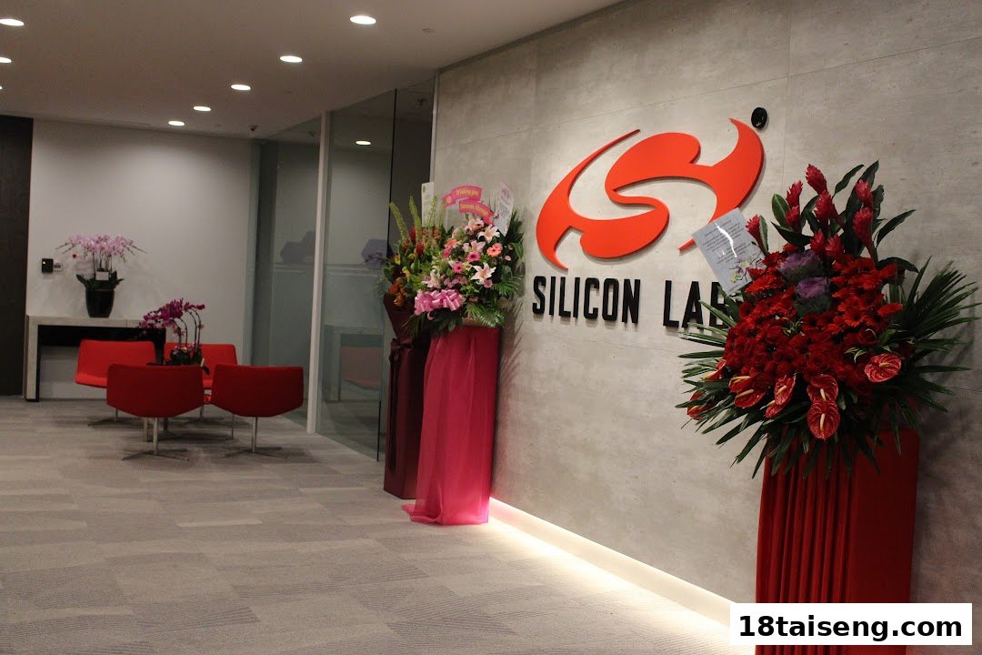 The modern lobby of Silicon Labs features a prominent logo, vibrant floral arrangements, and a comfortable red seating area.