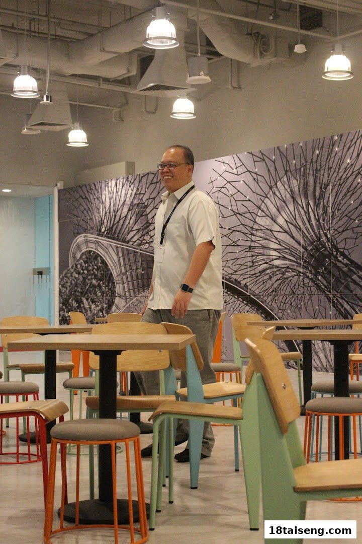 An employee smiles while walking through a modern, colorful cafeteria space at Silicon Labs.
