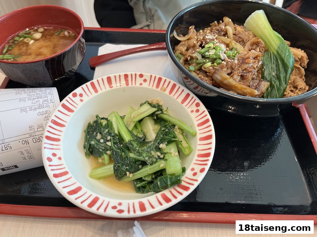 A delicious Sukiya meal featuring gyudon, miso soup, and a vegetable side dish on a tray.