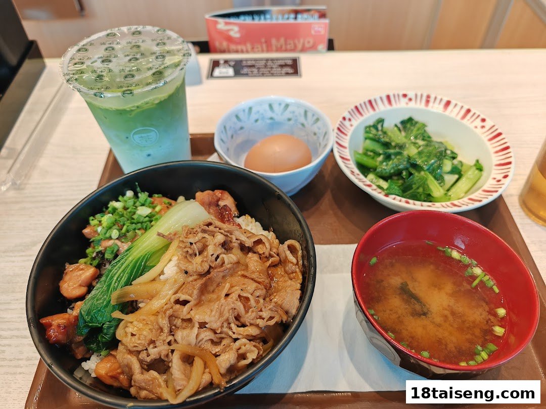 A delicious Japanese meal set featuring gyudon, chicken, miso soup, and a green tea drink.