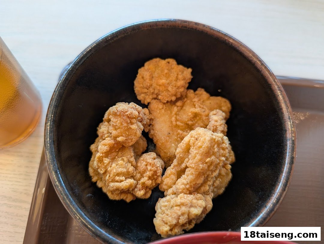 A close-up of crispy fried chicken pieces served in a black bowl, likely a side dish.