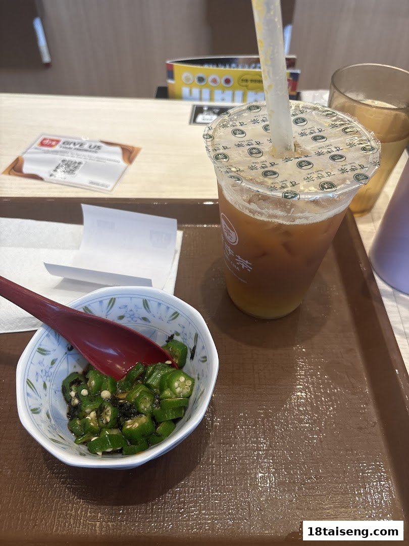 A close-up of a side dish of seasoned okra and an iced tea on a brown tray at Sukiya.