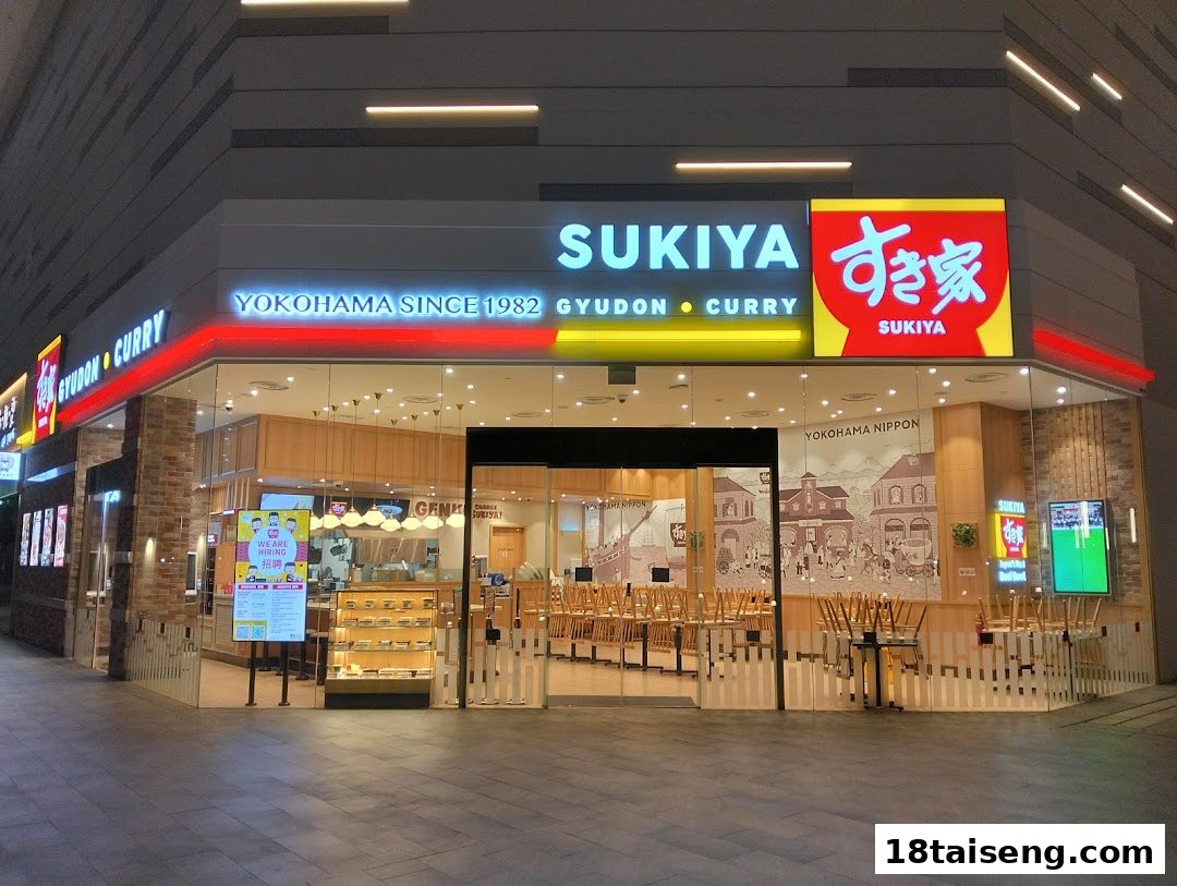 Exterior view of Sukiya Gyudon & Curry restaurant with illuminated signage and a welcoming glass facade.