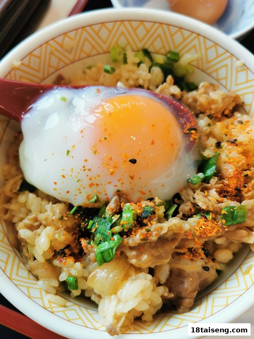 A close-up of a Sukiya gyudon (beef bowl) topped with a perfectly poached egg and seasonings.