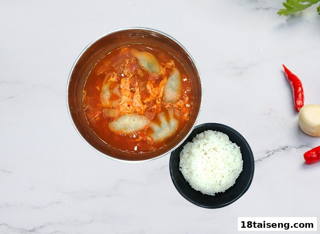A vibrant Korean stew with dumplings and egg, served with a side of white rice.