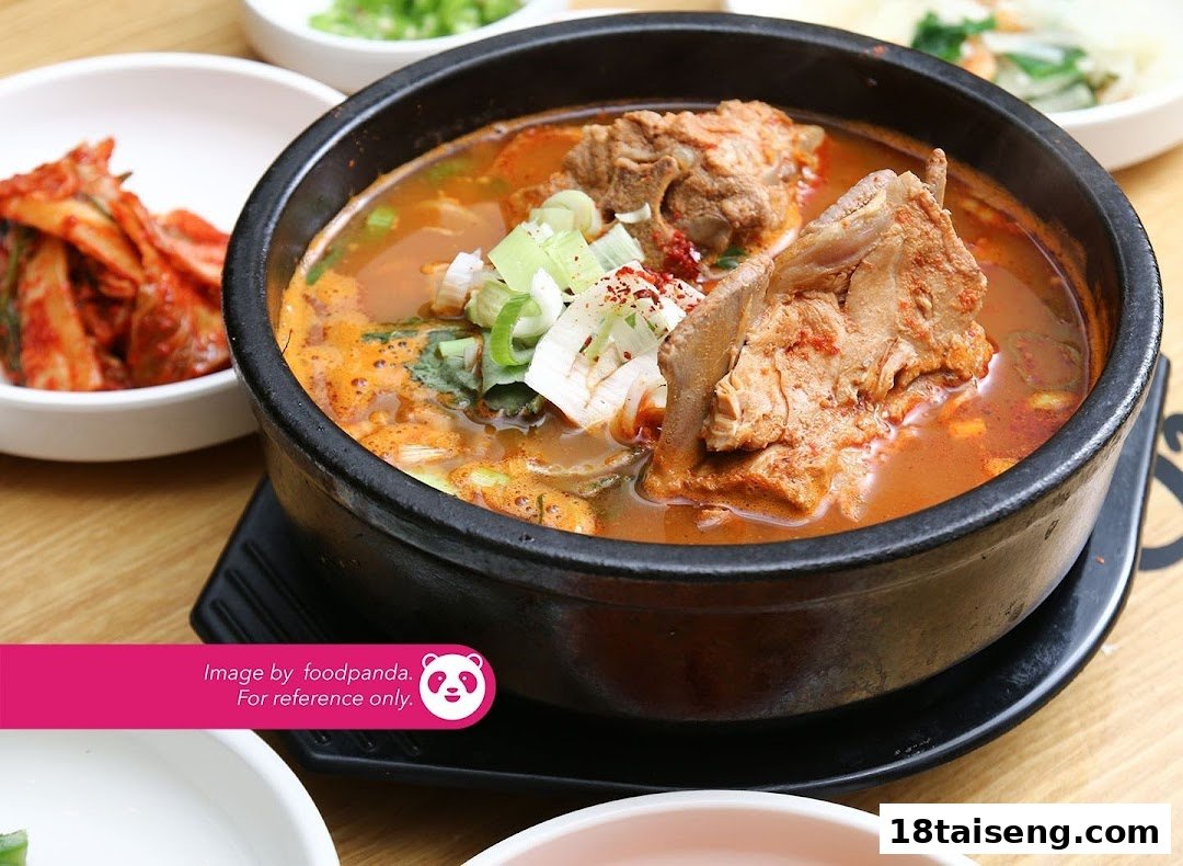 A vibrant Korean pork bone soup (Gamjatang) with green onions, served with traditional side dishes.