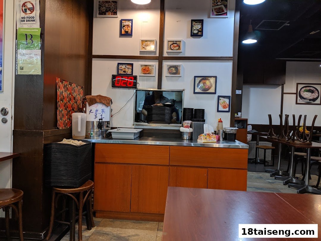 An interior view of Sunny Korean, featuring a service counter, framed food photos, and dining area.