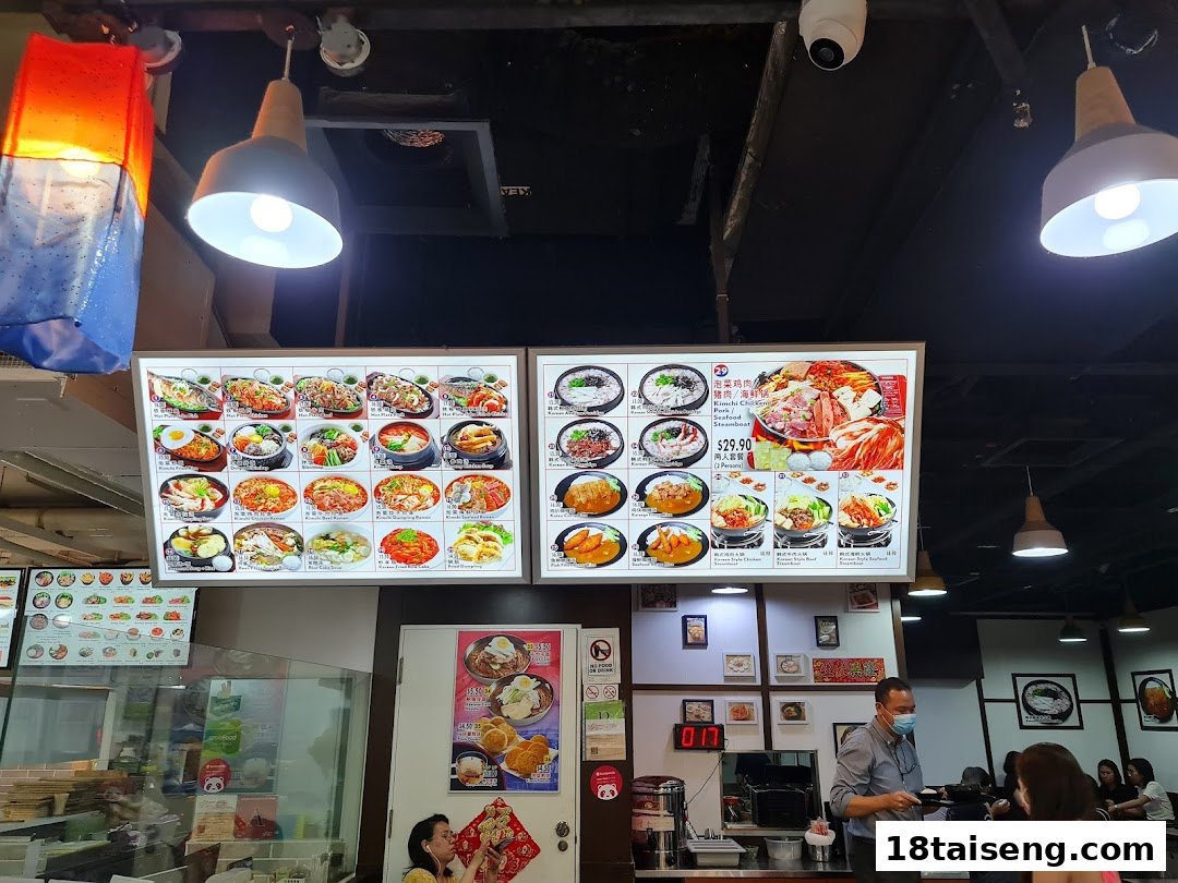 Interior view of Sunny Korean restaurant showcasing vibrant digital menu boards with various Korean dishes.