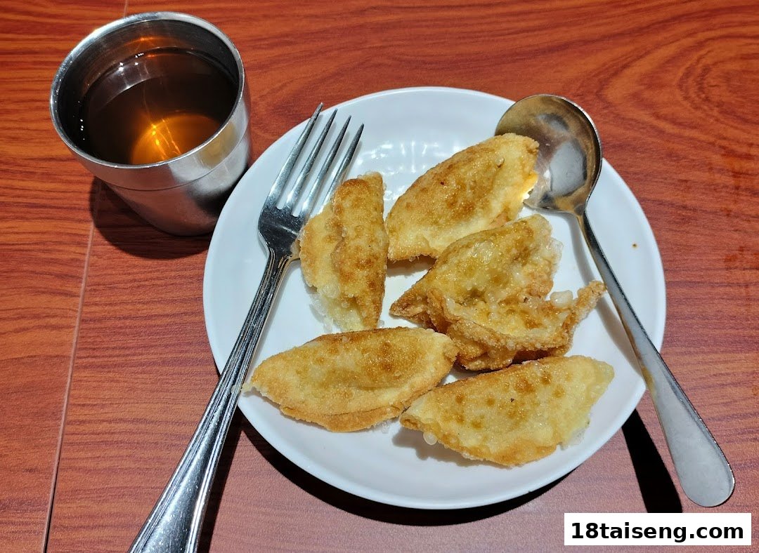A plate of golden-fried dumplings with a drink on a wooden table.