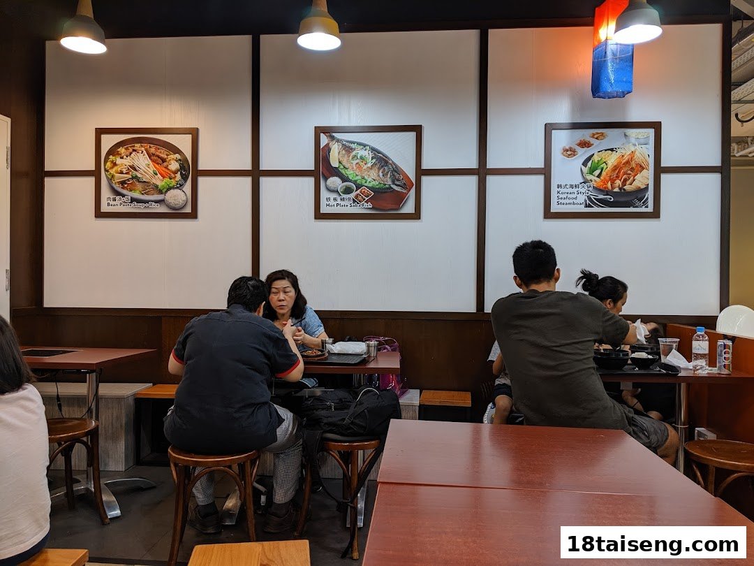 Customers enjoy authentic Korean cuisine in a cozy restaurant setting adorned with food posters.