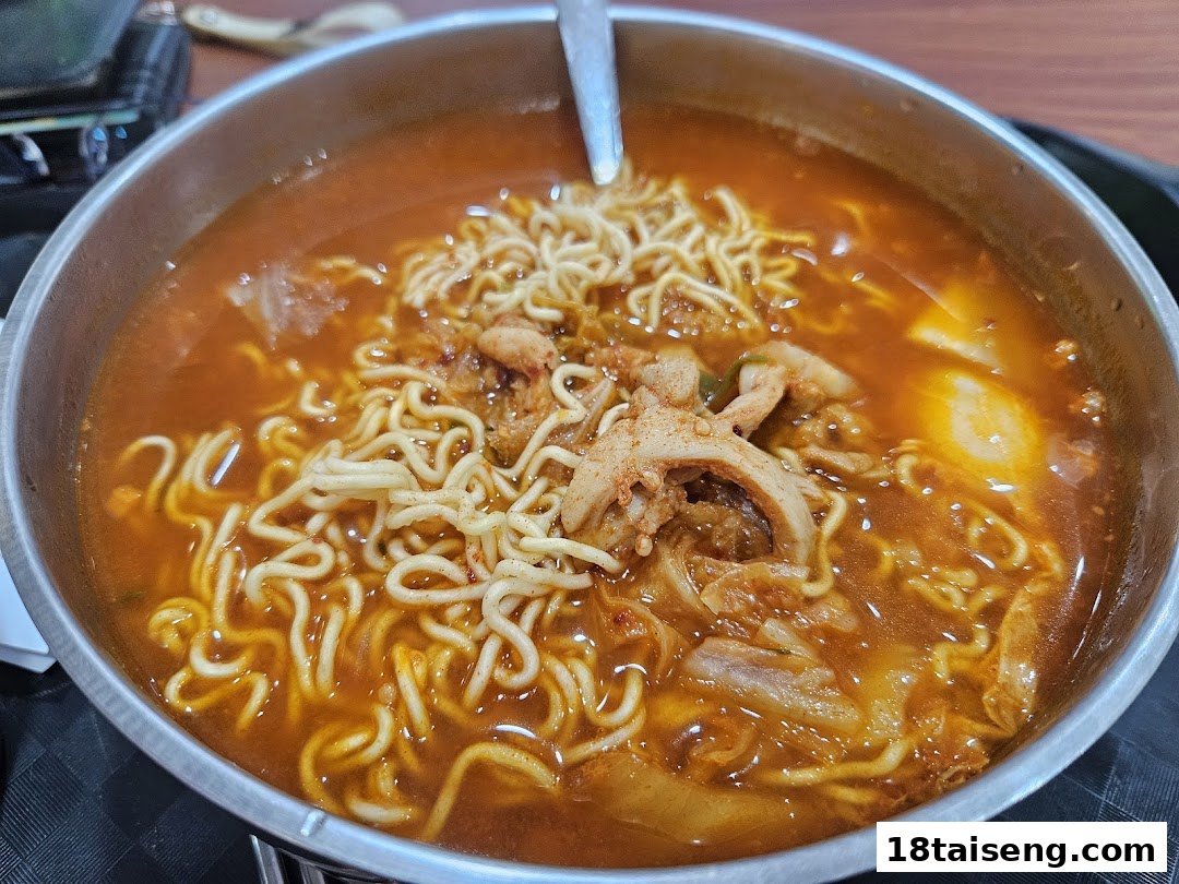A close-up of a vibrant, spicy Korean ramen dish served in a metal bowl.