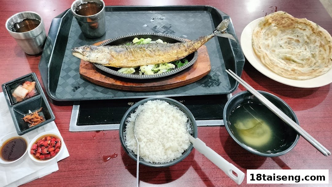 A delicious Korean meal featuring grilled fish, rice, soup, and various side dishes on a red table.