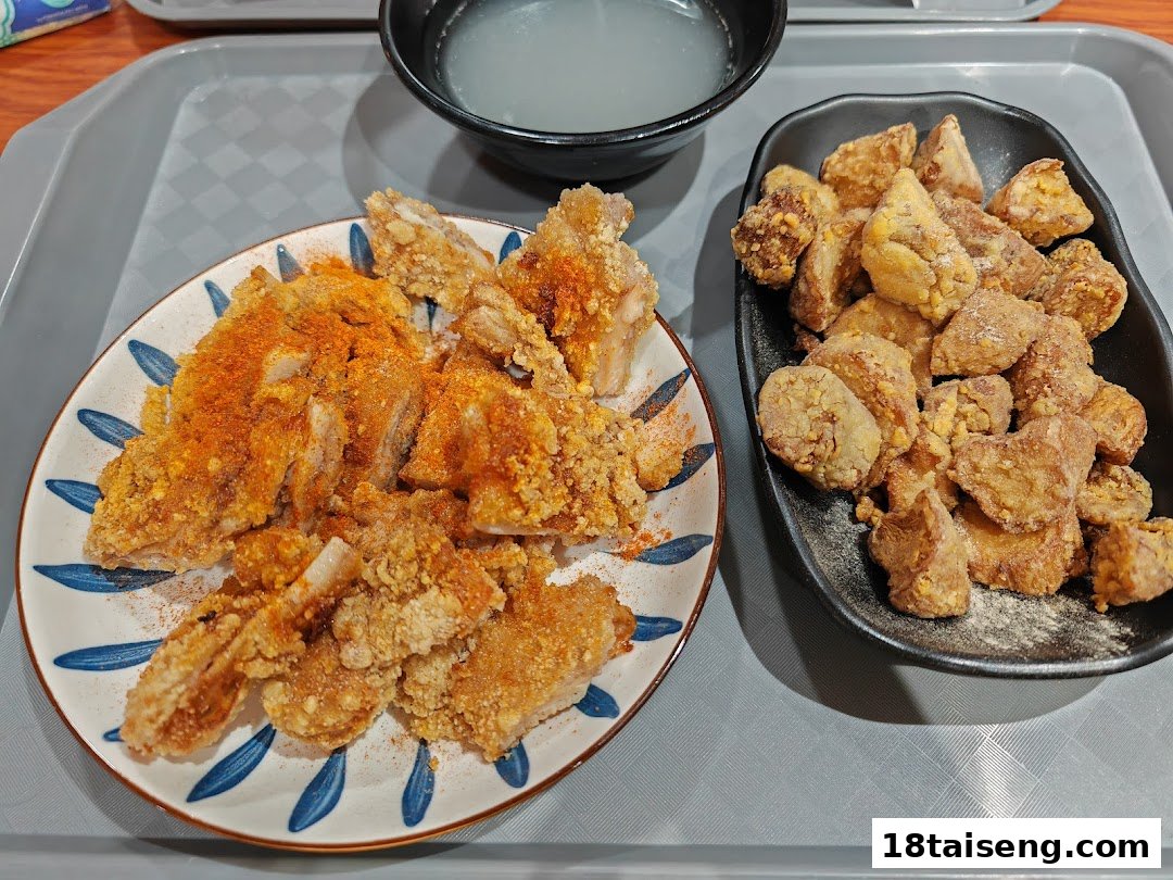 Two plates of crispy fried chicken and mushrooms, with a bowl of soup, served on a tray.
