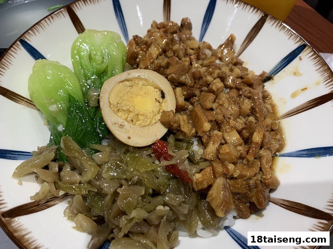 A close-up of a delicious Taiwanese braised pork rice (Lu Rou Fan) bowl with egg, bok choy, and pickled vegetables.