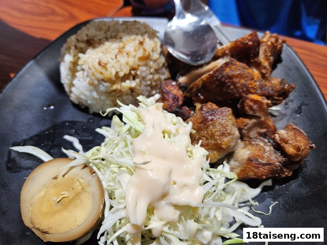 A delicious plate featuring seasoned rice, crispy fried chicken, fresh cabbage salad, and a braised egg.